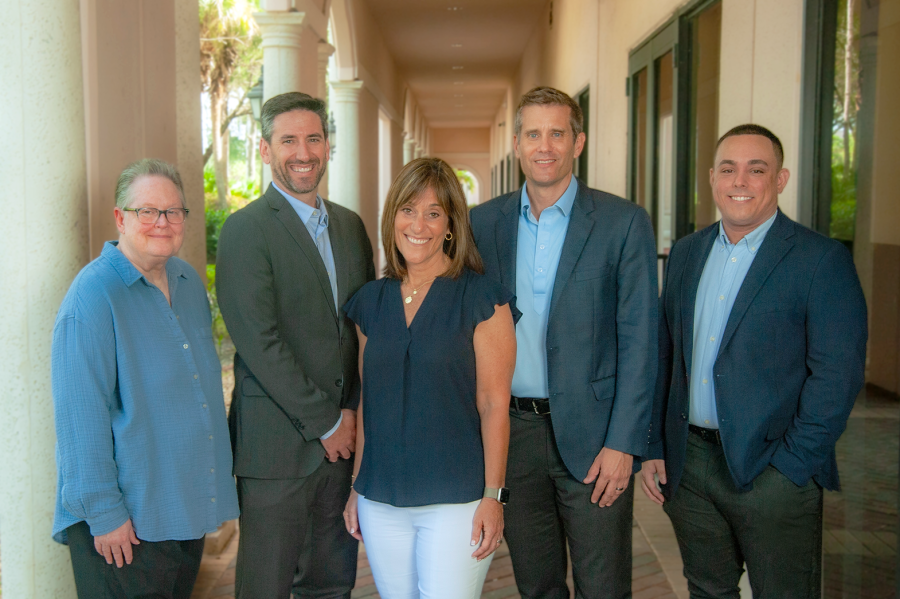 DWR_1319_B_Small Group portrait of the Core Wealth Management team standing together in a sunlit outdoor corridor.
